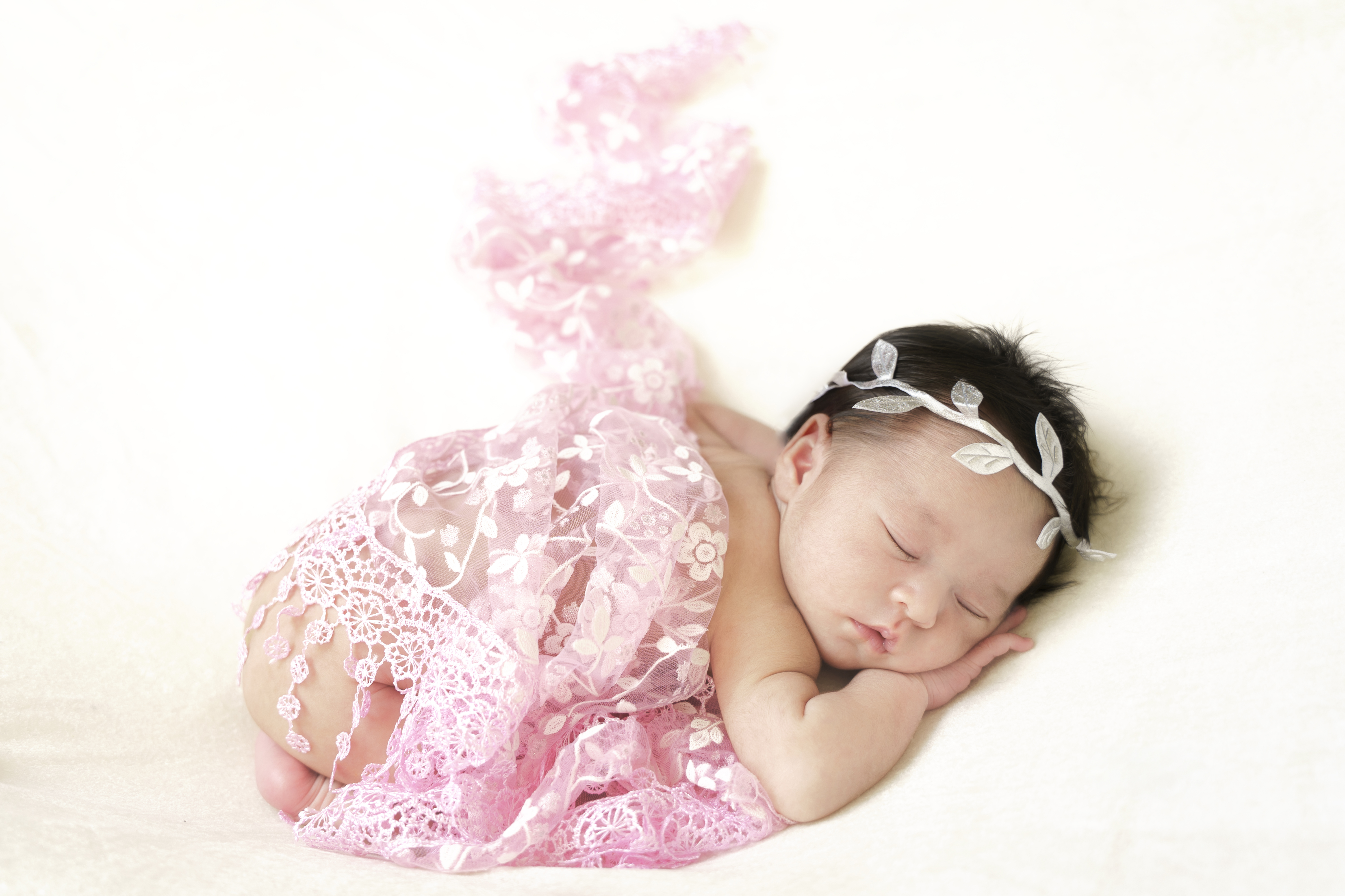 Recién nacida dormida arropada con encaje rosa